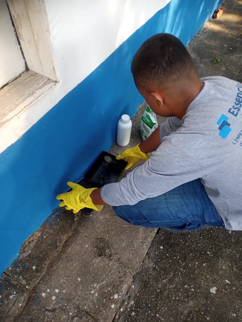 Técnico da Essencial Saúde Ambiental aplicando produto no rodapé externo de uma casa